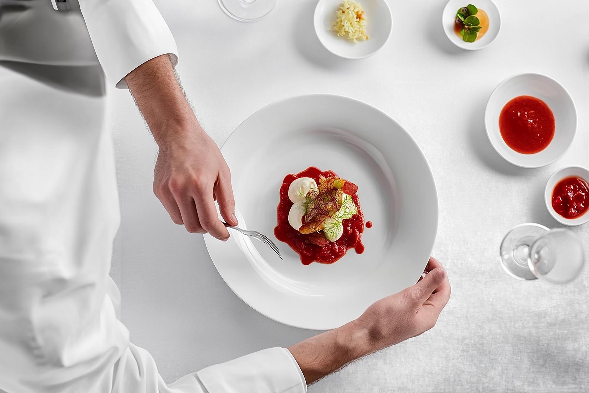 Chef arranging a plated dish in a calm studio